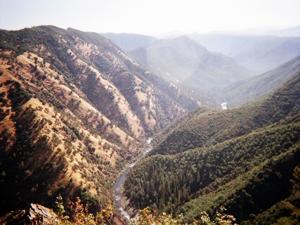 A bus driving on a winding dirt road to the river